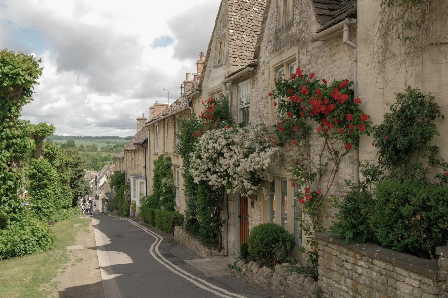 A honey-stone Cotswold lane with roses climbing the cottage walls.