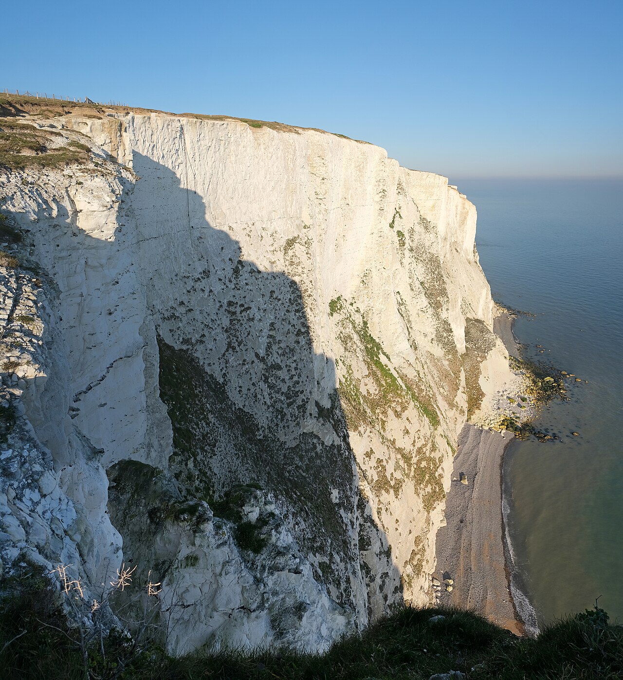 The white chalk cliffs at Dover, with grass on top and the sea below.